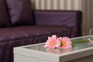 two pink flowers on a glass table in a bedroom at Villa Nicolli Romantic Spa Resort - Adults Only in Riva del Garda