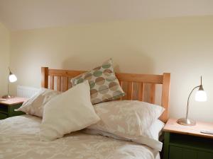 a bed with pillows on top of it with two lamps at Valeview Cottage in Great Malvern +4 photos