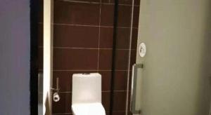 a bathroom with a toilet and a tiled wall at IU Hotels·Anshun Nanma Square in Anshun