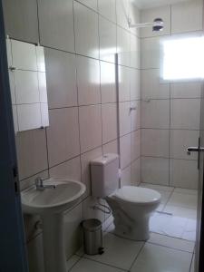 a white bathroom with a toilet and a sink at Hotel Cavalo Marinho Suítes in Caraguatatuba