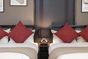 two beds in a hotel room with red pillows at Logements Tengachaya in Osaka +165 photos
