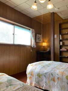 a bedroom with two beds and a window at ゲストハウス町家はま in Izumi-Sano