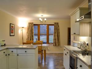 a kitchen with white cabinets and a dining room with a table at Taigh Seonaig in Glencoe