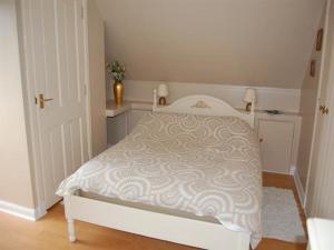a bedroom with a white bed with a white comforter at Bramble Cottage 1, 2 & 3 in Lochdon