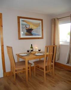 a dining room table with two chairs and a bottle of wine at Bramble Cottage 1, 2 & 3 in Lochdon