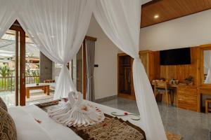 a bedroom with a bed with white drapes at Badawa Ubud Villa in Ubud
