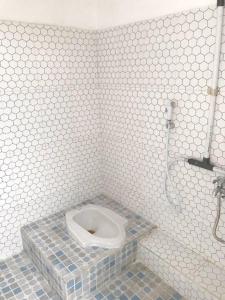 La salle de bains est pourvue de carrelage blanc et de toilettes dans une cabine. dans l'établissement Dehome near Pakuwon Mall (Syariah), à Surabaya