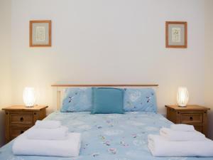 ein Schlafzimmer mit einem blauen Bett mit Handtüchern darauf in der Unterkunft Dairy Cottage in Talley