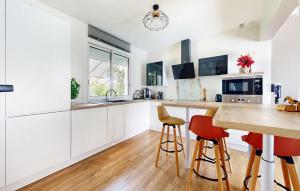 a kitchen with white cabinets and red bar stools at Belle Maison Avec Spa in Tournon-dʼAgenais