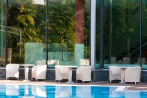 a group of tables and chairs next to a pool at Villa Nicolli Romantic Spa Resort - Adults Only in Riva del Garda