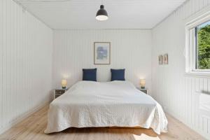 a white bedroom with a large bed with blue pillows at Spacious, Lovely Cottage In North Zealand in Melby