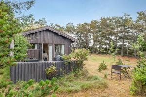 un petit hangar avec une table et une chaise dans une cour dans l'établissement Lovely Cottage Close To The North Sea, à Pandrup