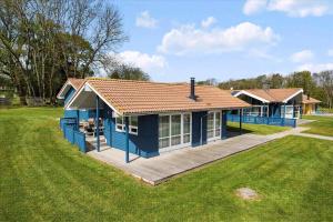 a blue house with a deck in a field at Beach, Starry Sky And Peace By The Water in Augustenborg