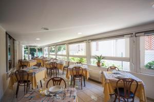 Hotel Taormina في ريتشيوني: مطعم به طاولات وكراسي ونوافذ