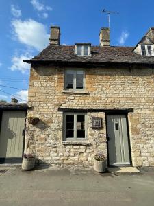 a stone house with two windows and two doors at Cozy Cotswold Burford Cottage in Burford