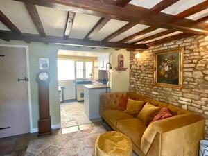 a living room with a couch and a stone wall at Cozy Cotswold Burford Cottage in Burford +11 photos