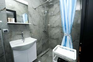 a bathroom with a sink and a shower with a blue shower curtain at Apartmani M&DŽ Bihać in Bihać +84 photos