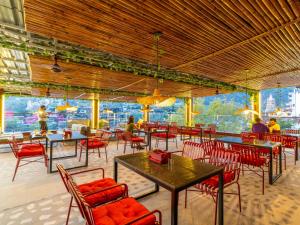 a restaurant with tables and chairs and people sitting at them at The Hosteller Rishikesh, Ganges in Rishīkesh +21 photos