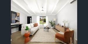 a white living room with a couch and a table at Lush Light Filled Escape with Pool Near Beach in Buderim