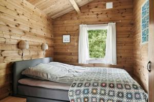 a bedroom with wooden walls and a bed with a window at Simple Life In Traditional Home By Lyngså Beach in Sæby