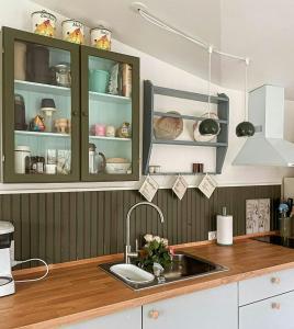 a kitchen with green cabinets and a sink at Retro Cottage With Fjord View in Storvorde