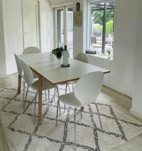 a dining room table with white chairs in a room at Retro Cottage With Fjord View in Storvorde