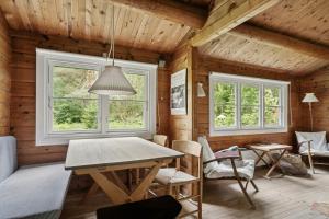 Un comedor con mesa y sillas y ventanas. en Log Cabin Near Vesterstrand On Anholt, en Anholt