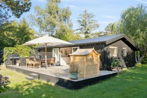 a wooden deck with an umbrella and a house at Holiday Home On Hilltop By Sejerø Bay in Nykøbing Sjælland