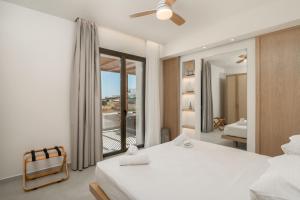 a bedroom with a white bed and a balcony at Lavea Suites Milos in Pollonia +79 photos