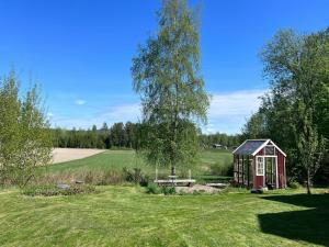 a small red shed in the middle of a field at Cultural Cottage By Lake Fryken In Värmland in Östra Ämtervik
