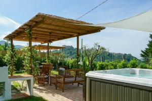 a patio with a hot tub and a wooden umbrella at Tuscan Villa With Sea View And Jacuzzi in Fosdinovo