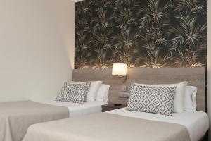 two beds in a hotel room with a wallpaper at Hotel Puerto Palace in Puerto de la Cruz
