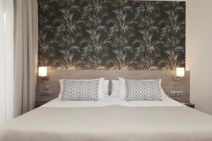 a bedroom with a white bed with two pillows at Hotel Puerto Palace in Puerto de la Cruz