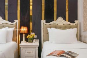 a bedroom with two beds and a book on a night stand at SILK CLASSIC HOTEL & TRAVEl in Hanoi