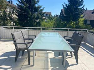 a glass table and four chairs on a patio at 3 bedroom apartment in Leverkusen incl parking-near Messe Deutz-Lanxessarena-Bayarena in Leverkusen