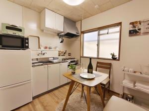 a kitchen with white cabinets and a table and a window at ゲストハウス DiDi 103 Private Apt near Park 10min from Station Netflix in Tokushima