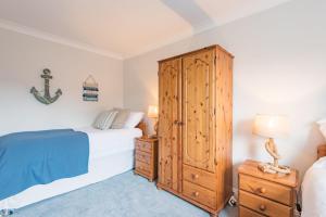 a bedroom with a bed and a wooden cabinet at The Landing in Hythe
