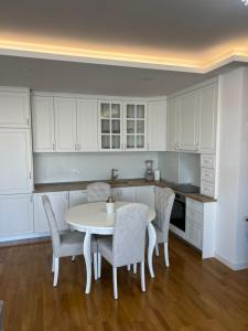 eine Küche mit weißen Schränken und einem Tisch und Stühlen in der Unterkunft Cozy central apartment in Čapljina