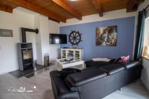 a living room with a black leather couch and a fireplace at 58 Ferienhaus Sonnenblick in Avendorf auf Fehmarn