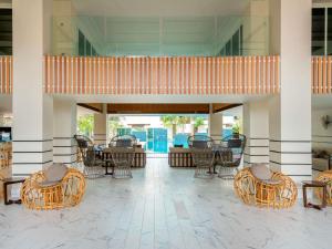 eine Lobby mit Stühlen und Tischen in einem Gebäude in der Unterkunft Mercure Langkawi Pantai Cenang in Pantai Cenang