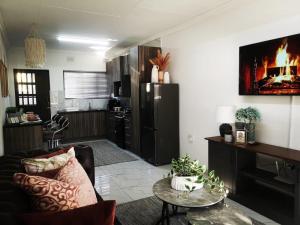 a living room with a couch a table and a refrigerator at Carissa Street Self-catering Units in Burgersfort