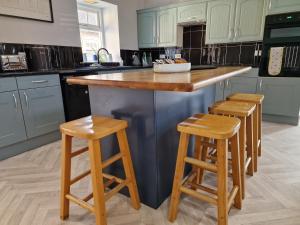 a kitchen with a island with two wooden stools at Southbarn - Spectacular Country Home in Winestead