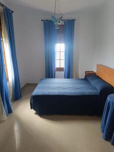 a bedroom with a bed with blue curtains and a window at La Buena Vida, el Palmar in El Palmar +9 photos