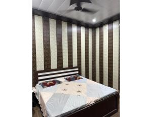 a bedroom with a bed with a striped wall at SLH guest house in Faizābād