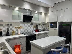 a kitchen with white cabinets and black appliances at 2 bedroom home Ikeja in Ikeja +8 photos