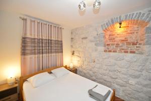 a bedroom with a bed and a brick wall at Kuzman Apartments in Kotor