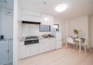 Una cocina con gabinetes blancos y una mesa con sillas. en Kasai Light Luxury Hotel 201, en Tokio