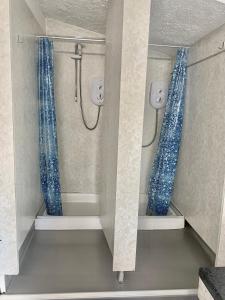 a shower with blue shower curtains in a bathroom at Sleeping Giant outdoor adventure flat in Pen-y-cae