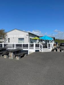 a building with a white fence and tables and umbrellas at Bude Holiday Resort Peace And Quiet in Bude