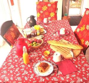 a table with a red table cloth with food on it at Chambres d'hôtes Sauvian in Sauvian